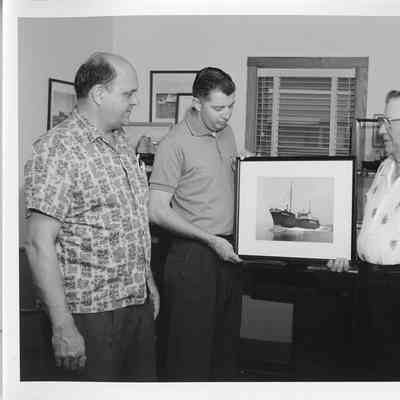 Frank Tachovsky, Ronald Berg, and Captain John roen holding photo of trawler Sturgeon Bay