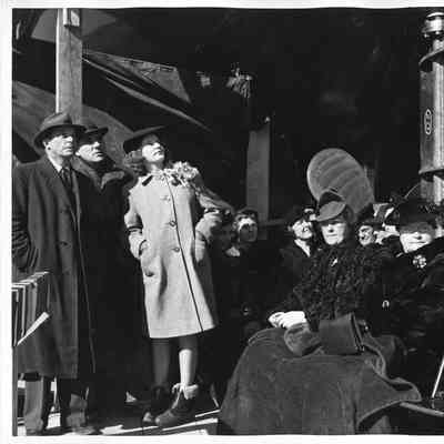 Three people standing among group of people sitting at Peterson Boat Works boat launch