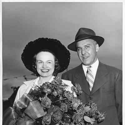 Mrs. George Reeke holding roses alongside husband