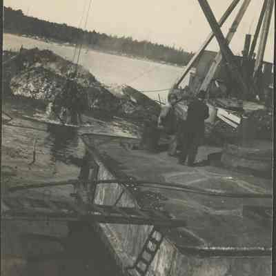 Two men on barge in front of dredge