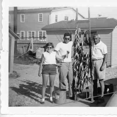 The Emmanuel's standing near a bunching of hanging fish