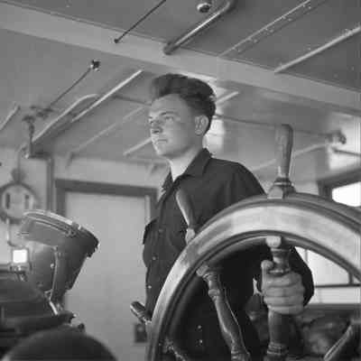 Man at wheel of United States Lighthouse Tender Hollyhock