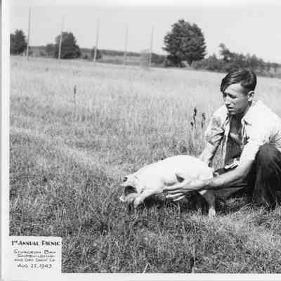 Man holding pig at SBSB&DD Co. 1st annual picnic August 22, 1943