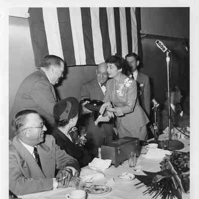 Man and woman holding folded flag at Badger/Spartan christening dinner September 6, 1952