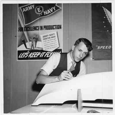 Man in suit drawing drafting lines on half hull model