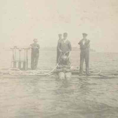 Diver in bell helmet with workmen