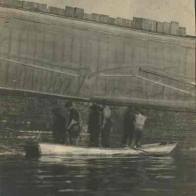 Workers on skiff next to hull