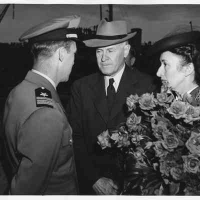 Mr. and Mrs. Sydney T. Smith holding roses with naval officer