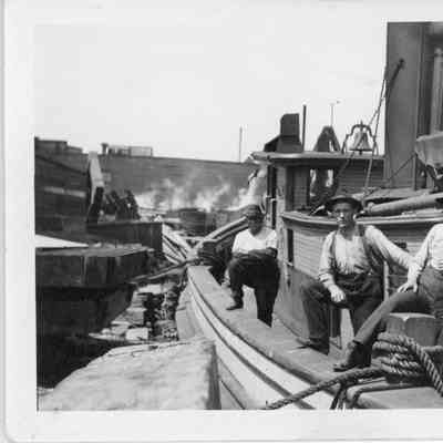 Three men standing on deck of docked vessel