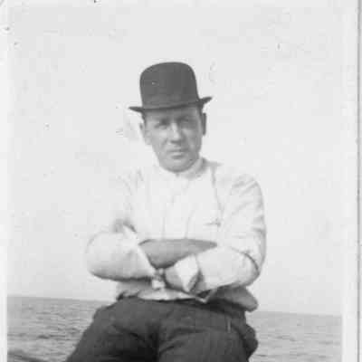 Man in bowler hat sitting with arms crossed