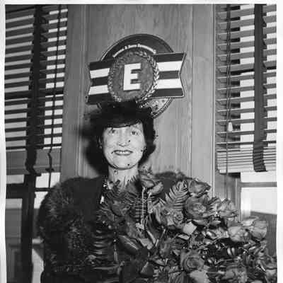 Mrs. W. H. Gallieane holding roses in office