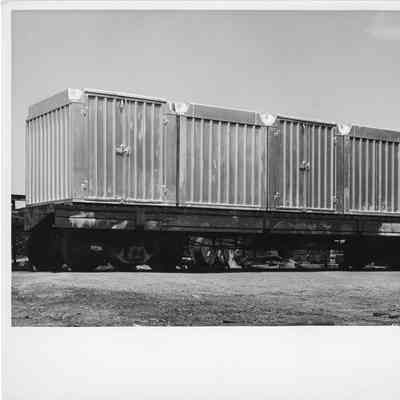 Multiple Safewy containers laying on a flatbed freight car