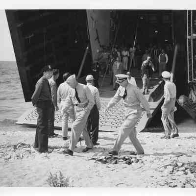 Group of men standing on landing platform of LST-1166 with men on shore, September 9, 1953