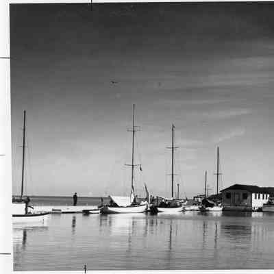 Sailboats with sails down and a couple of other vessels dockside
