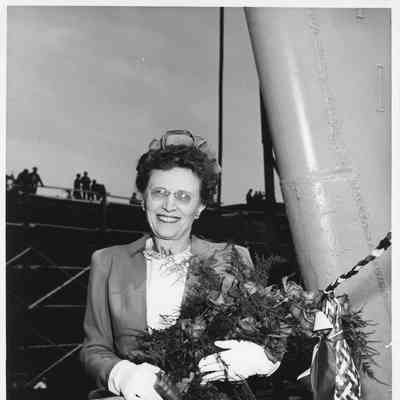 Woman holding flowers and christening bottle next to Poinsett