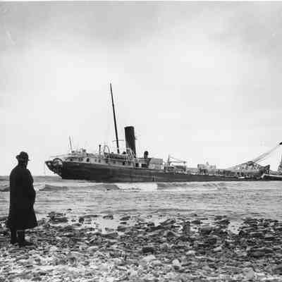 Stranded vessel Sinaloa with man standing on rocky shore