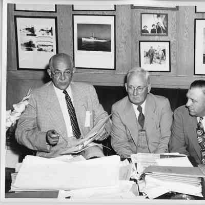 two unidentified men and C. Ray Christianson in office