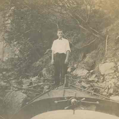 Young man standing on shore next to skiff