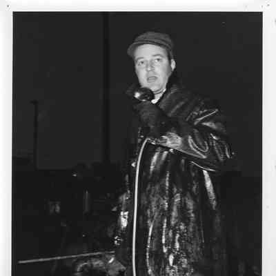 Man in raincoat talking at launching of LST-1166 1952