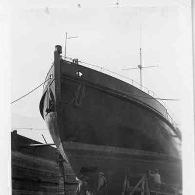 3 men working on hull of drydocked vessel