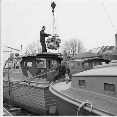 Man lowering engine into US Army Boat at Sturgeon Bay Boat Works