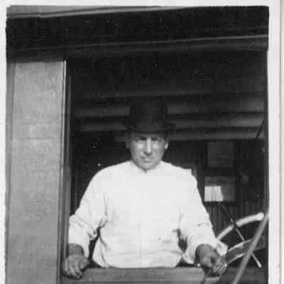 Man in bowler hat standing in pilot house