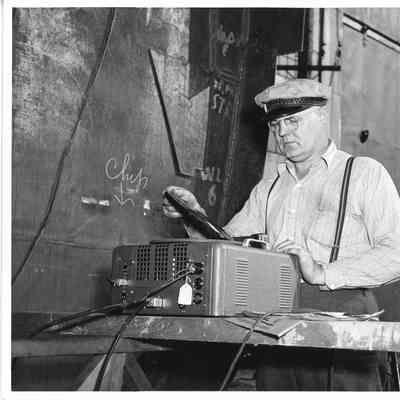 Unidentified man placing phonograph record on turn table at PC-1225 ship christening