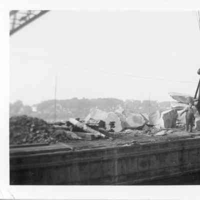 Crane barge carrying stone with man on deck
