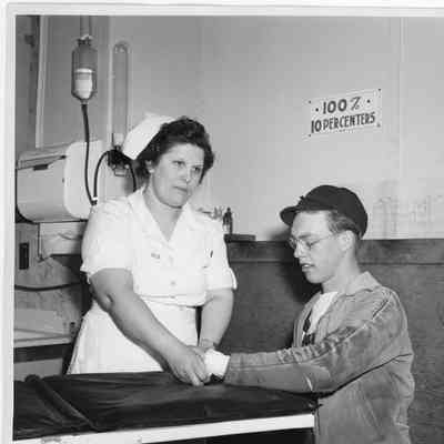 Nurse Jeannie Anderson Lensmeyer bandaging mans left wrist April 19, 1943