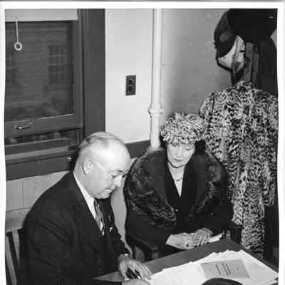 L.D. Smith and Mrs. Gallieane sitting by desk signing documentation