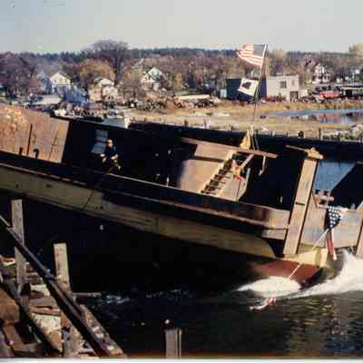 Brown and yellow ship launching with SBSB&DD Co. in background