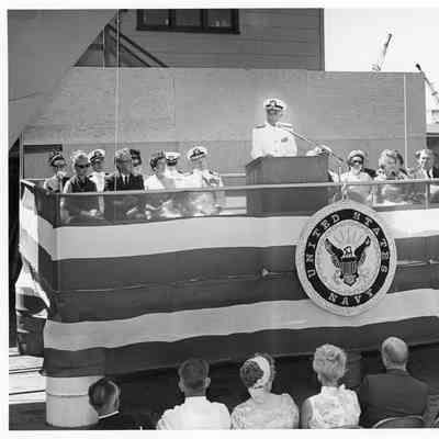 Man speaking at podium during the christening of PG-95 USS Defiance