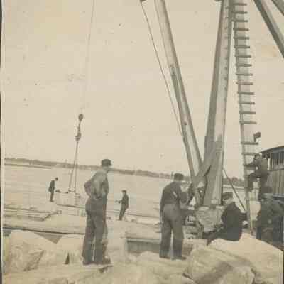 Workers loading large quarry stone onto barge