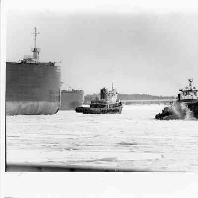 Two ships being towed by Jimmy L with a bridge in the background