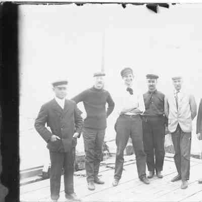 Seven men posing for photo on deck