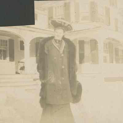 Woman in fur coat in front of large building