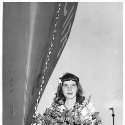Woman holding flowers next to PC-1175 at ship christening