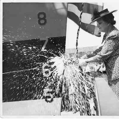 Mrs. M.W. Zeidler smashing bottle of champagne on bow of PC-825 1944
