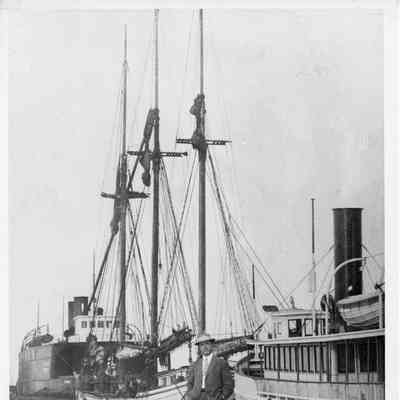 Schooner George A. Marsh with steamships Wau-kon and St. Ignace docked behind man