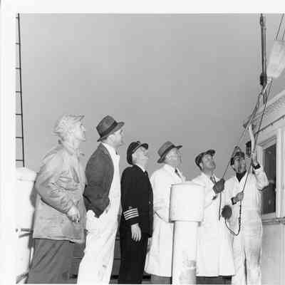 Christy Corp employees raising broom on deck of Elton Hoyt II