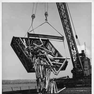 Crane dumping baskets of logs into the hold of the Resolute