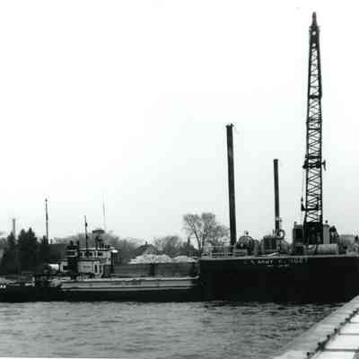 Tug Racine and crane barge filling pier with stone 1974