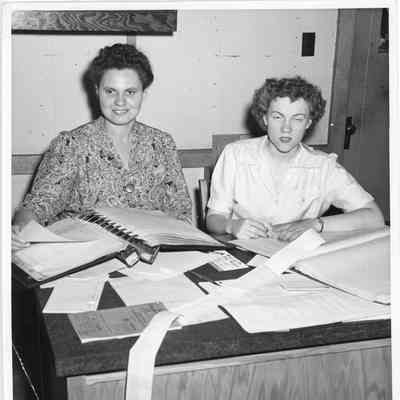 Two women writing in ledgers