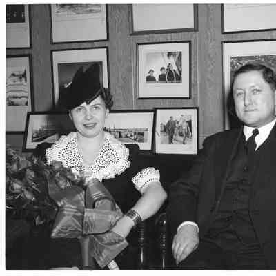 Sponsor with roses sitting next to unidentified man in dark suit