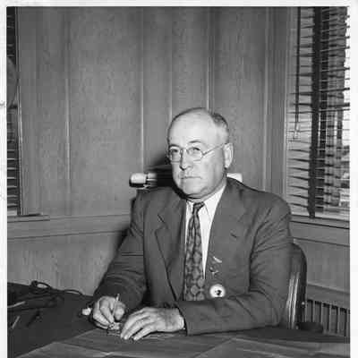 Leathem D. Smith at desk with blueprint