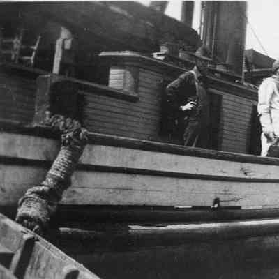 Two people in diving suits without helmets on boat