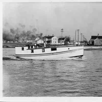 Fishing tug underway with homes in background
