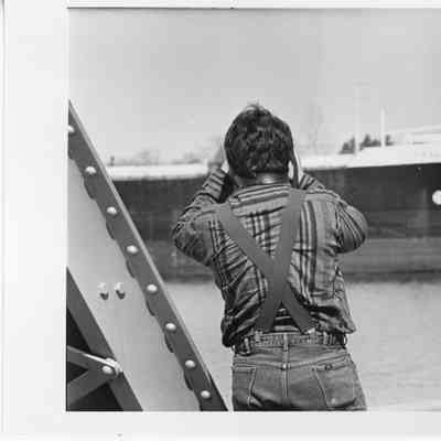 Man taking photo of ship while standing between beams of bridge 1993