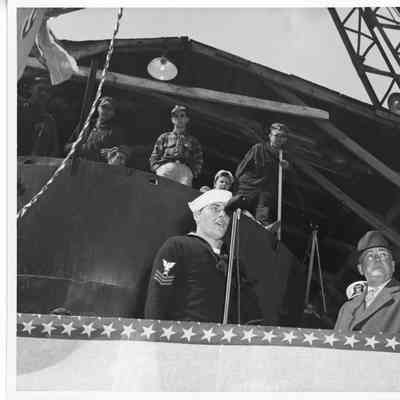 Unidentified navy man at microphone alongside Leathem D. Smith