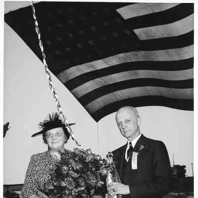 PC-825 ship sponsor Mrs. Zeidler holding flowers alongside Frank L. Fawcett holding christening bottle